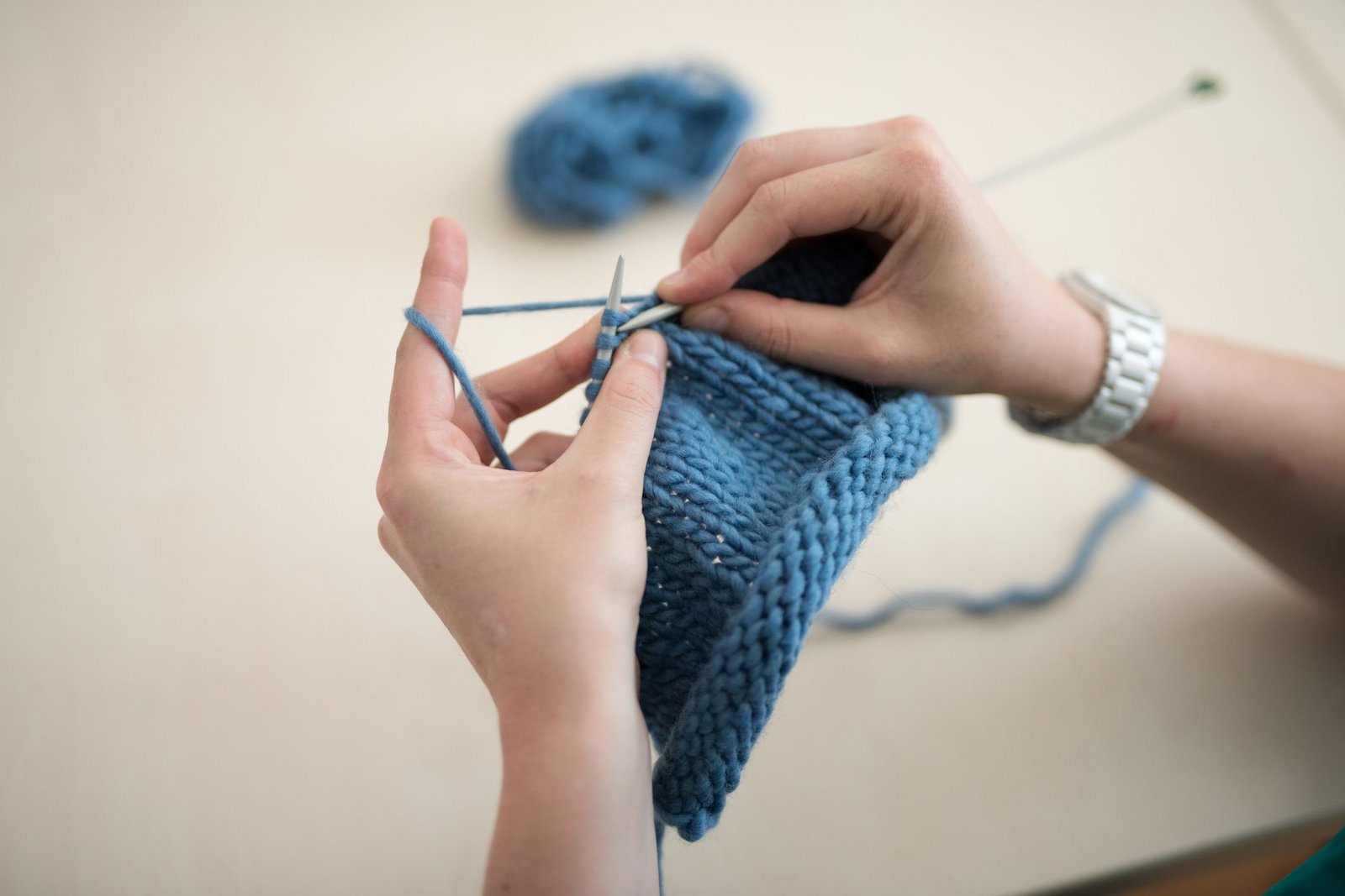 Zwei Hände mit Stricknadeln, Strickarbeit und Wolle, Detail